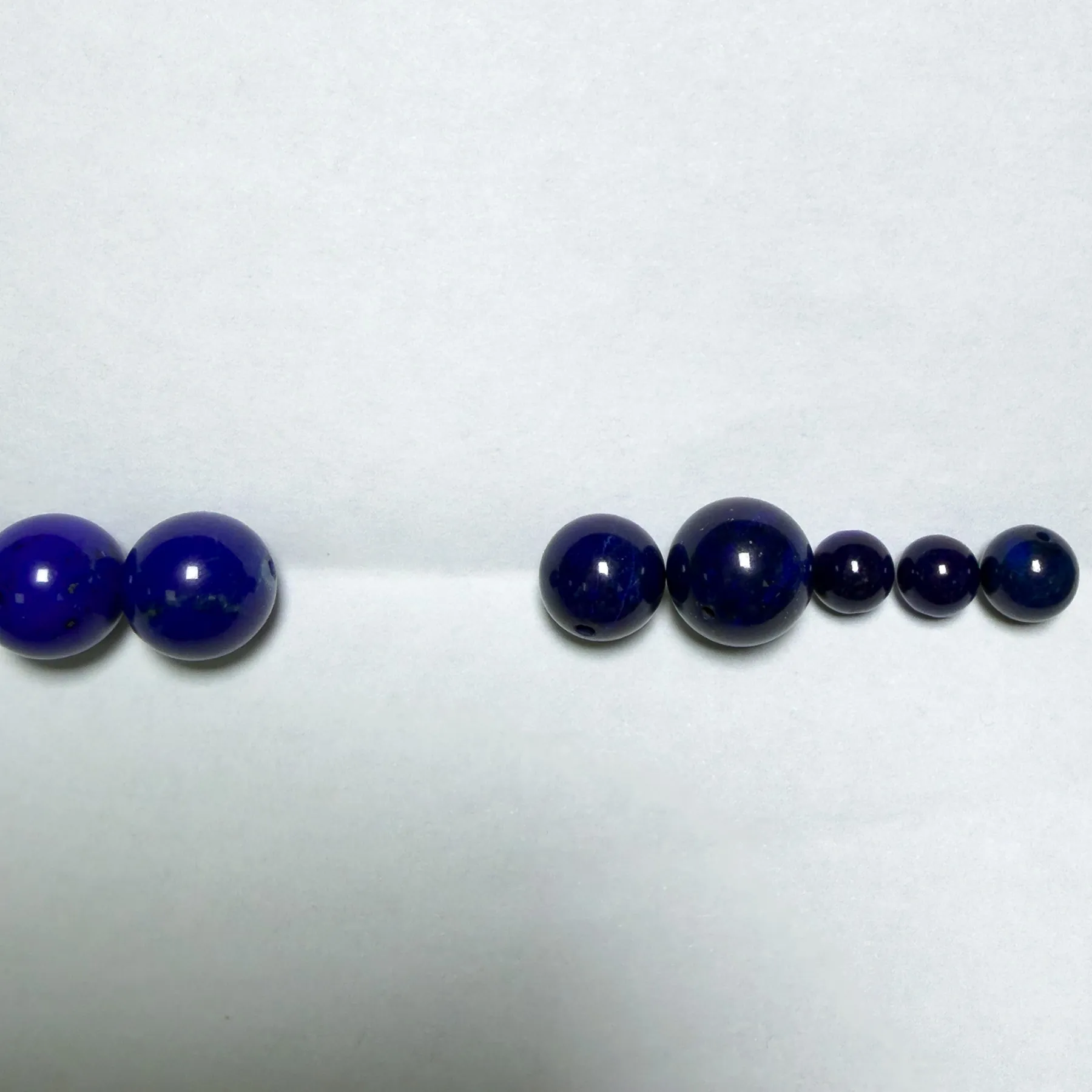 Very dark natural lapis compared with brighter blue lapis on a white background