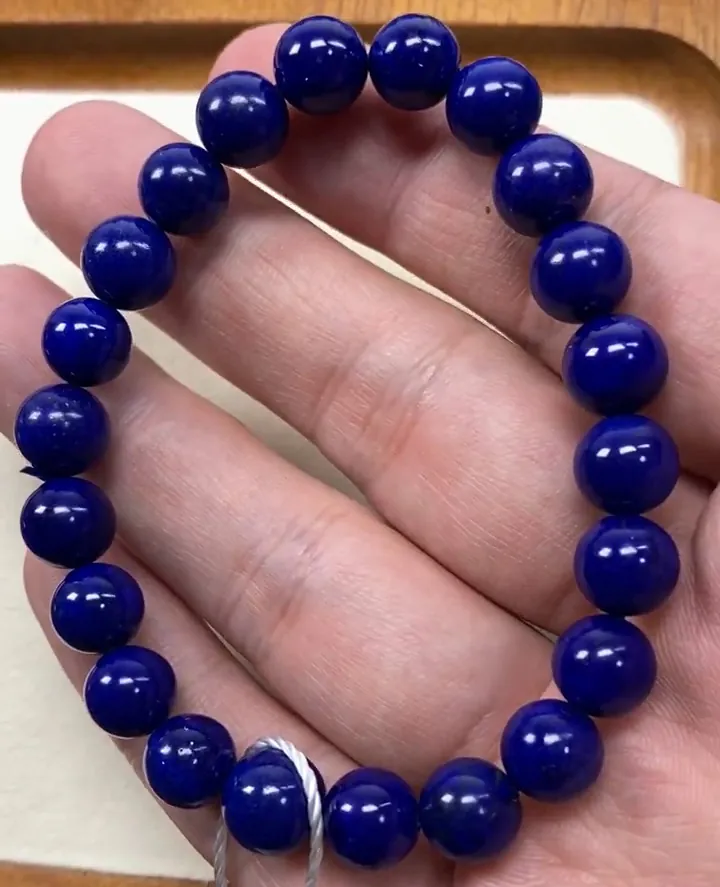 Deep blue lapis lazuli bracelet with saturated, even blue round beads held in a hand