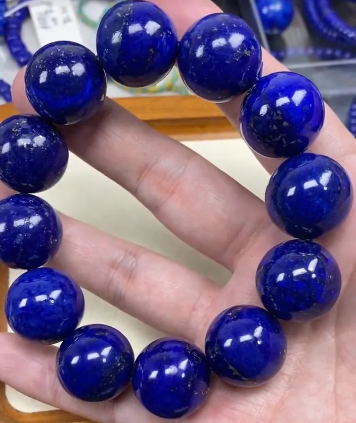 Large polished deep-blue lapis beads with mottled mineral variation across their surfaces