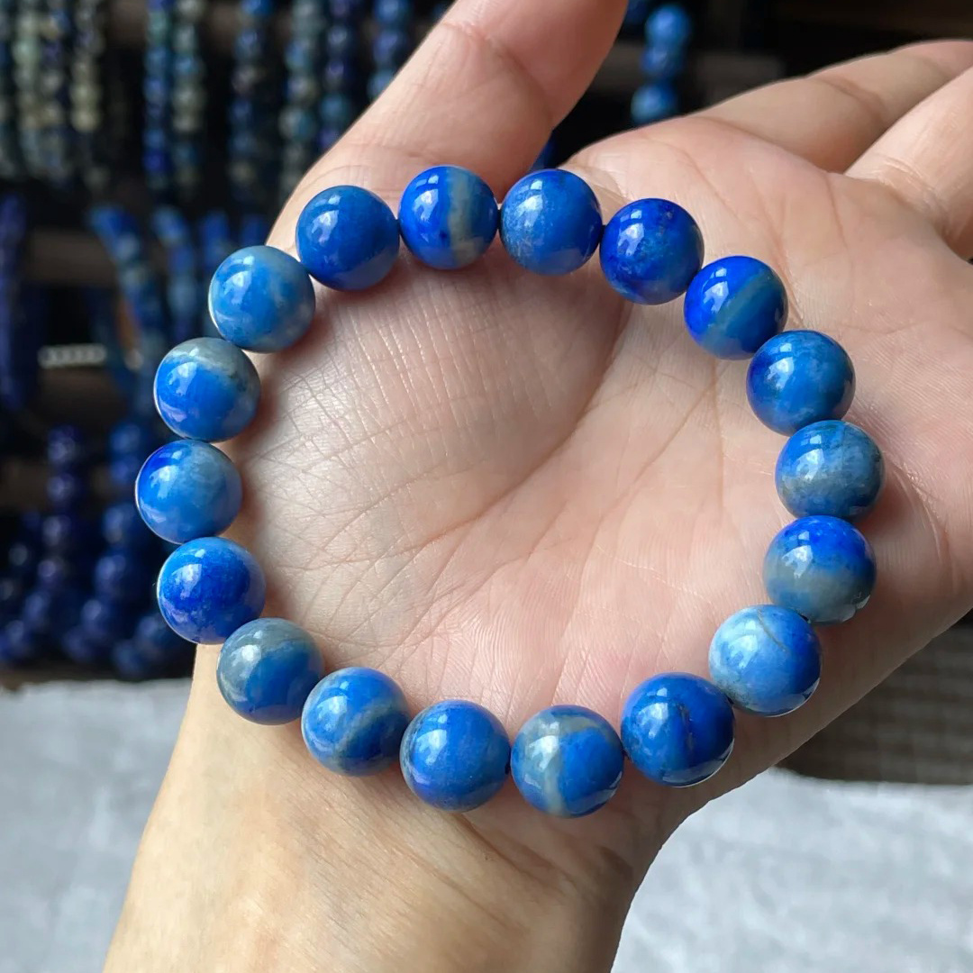 Round denim lapis lazuli bead bracelet showing blue and pale mottled color in a hand