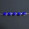 Front close-up of five blue lapis stones and small clear accents in silver settings