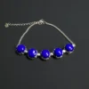 Five round blue lapis stones in silver settings with clear accents, chain and lobster clasp