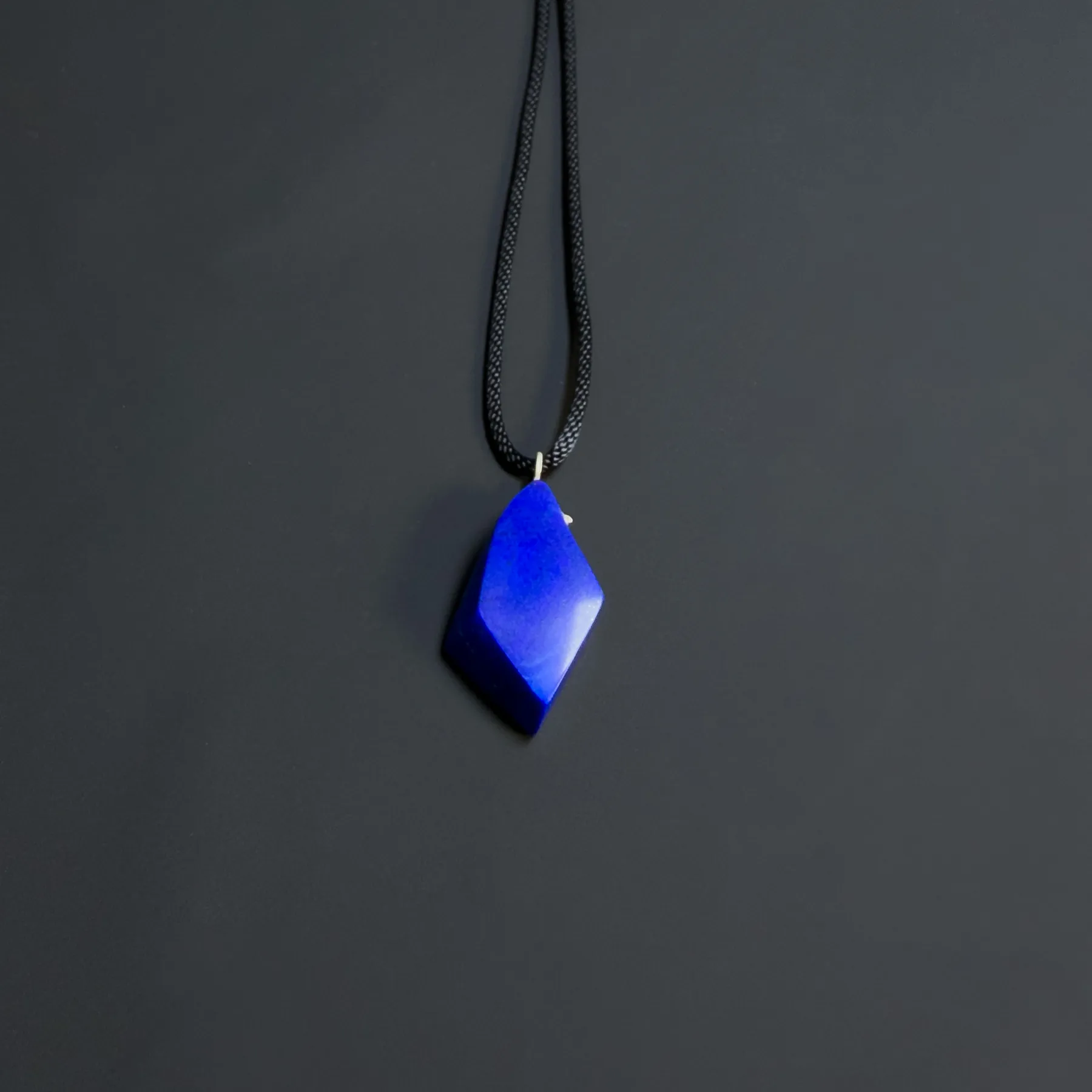 Wider view of the royal-blue freeform lapis pendant suspended from a long black cord