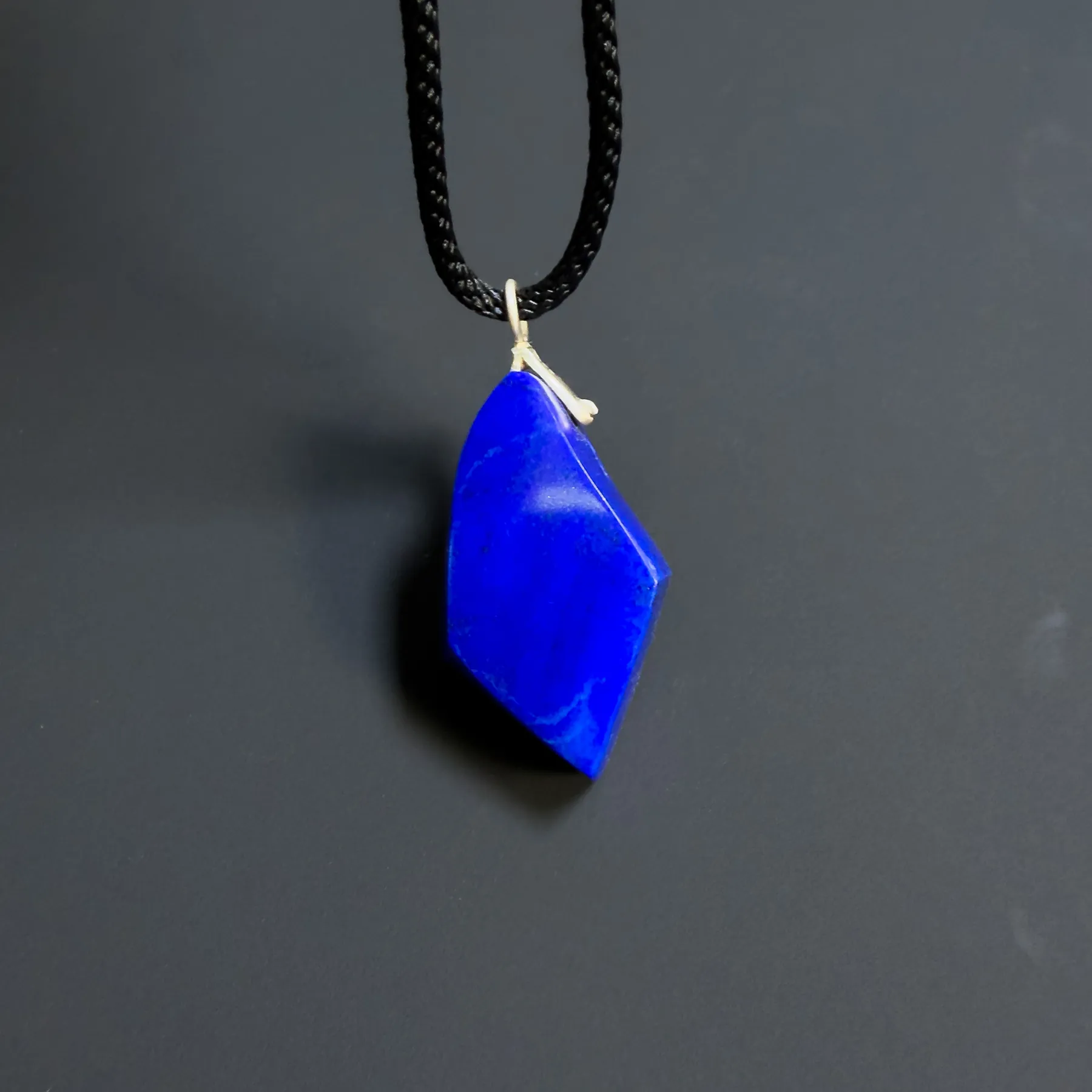 Oblique view of the blue lapis pendant with silver fitting and a pale line near the edge