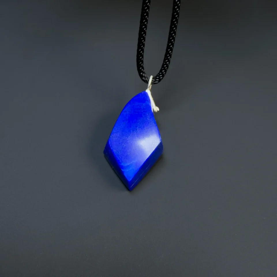 Upright front view of a faceted blue lapis pendant showing its uneven geometric outline