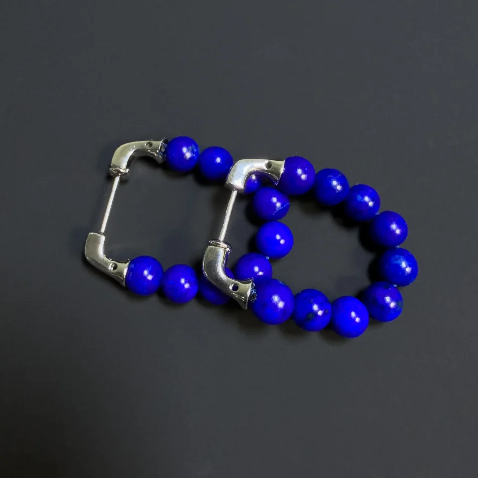 Angled pair of blue lapis bead earrings with their silver posts visible