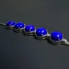 Low-angle close-up of domed lapis stones, silver prongs and openings beneath the settings