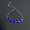 Lapis lazuli bracelet arranged with its lobster clasp open beside the extended silver chain