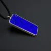 Diagonal close-up of the royal-blue lapis face framed by silver with the black cord visible
