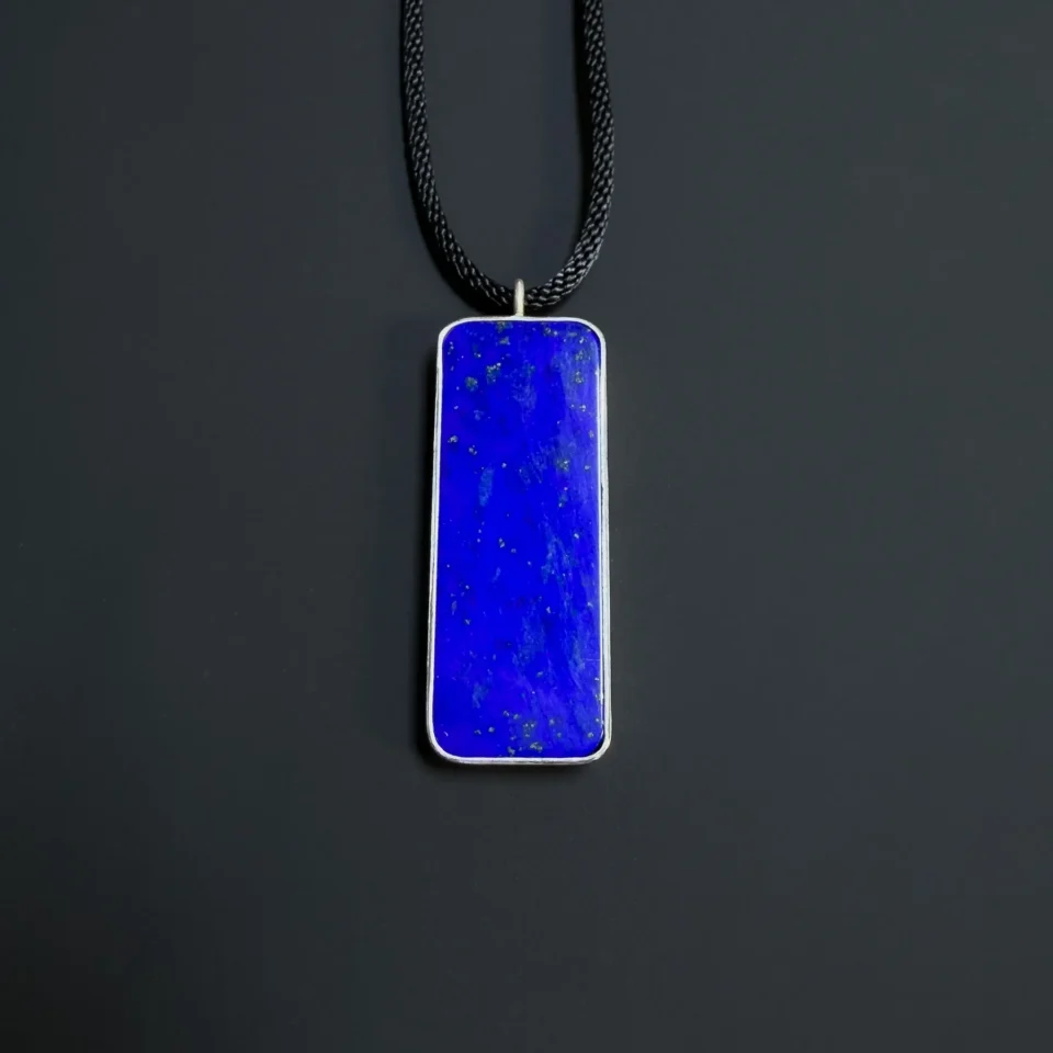 Straight-on front view of the long blue lapis pendant hanging from a black cord