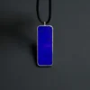 Upright front view of the royal-blue rectangular lapis pendant with black cord above