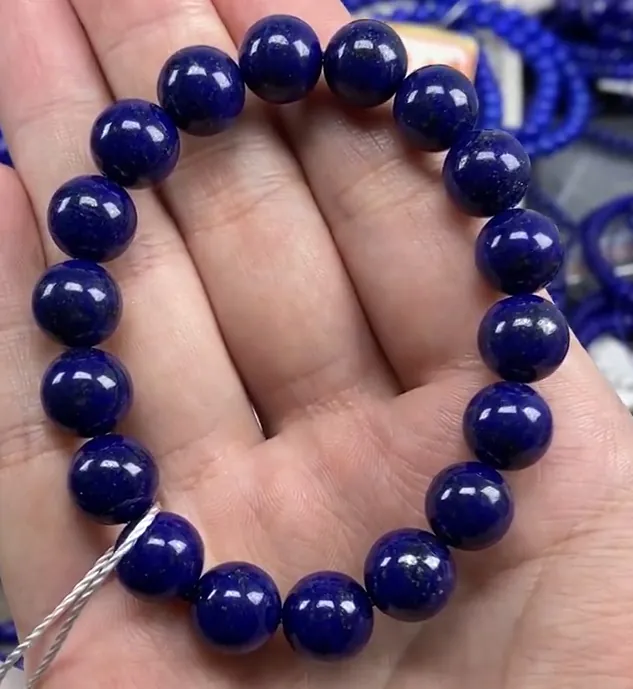 Very dark blue lapis bracelet held in a hand with the blue still visible